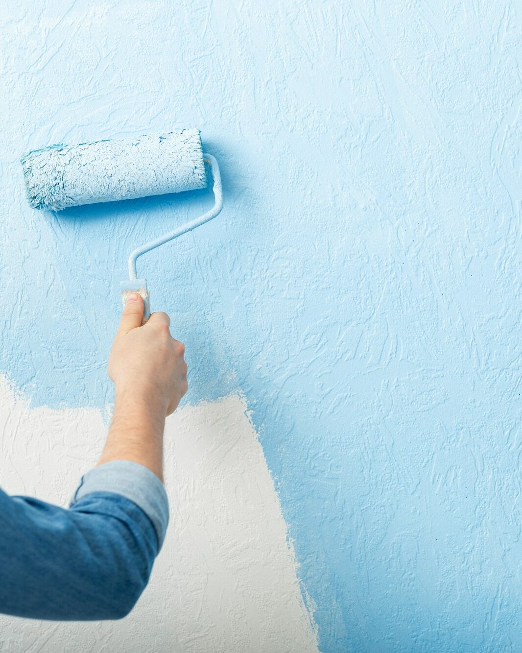 Paints texture wall with roller in blue